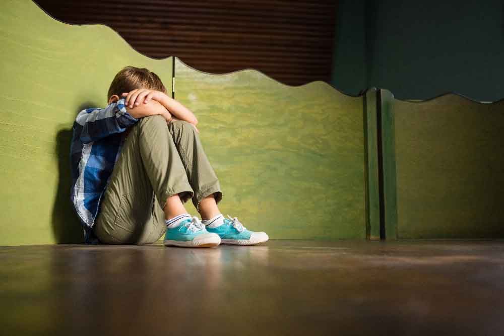 young man sitting on floor head fallen into crossed arms